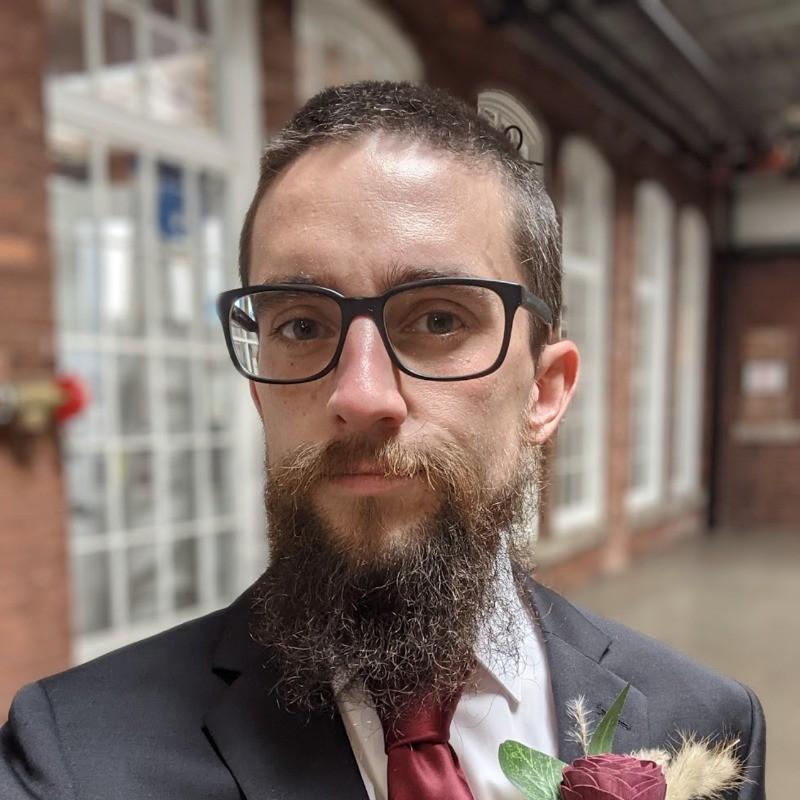 Tom Goldrick in a suit and glasses.